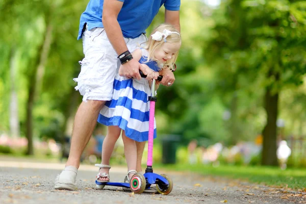 Отец показывает дочери, как ездить на скутере — стоковое фото