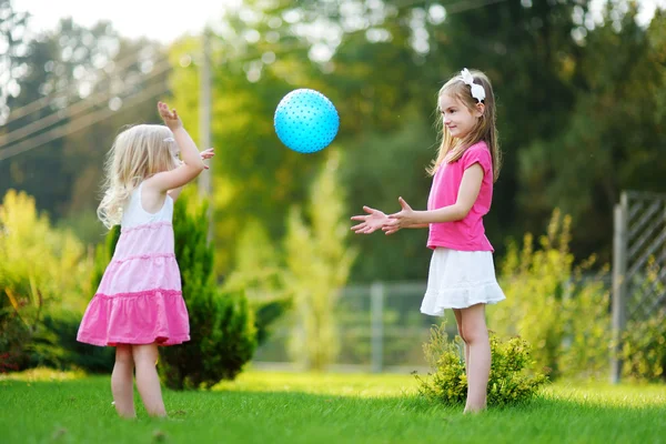 Сестры играют вместе в мяч на траве — стоковое фото