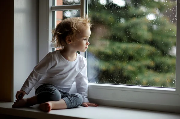 Tout-petit fille regardant par la fenêtre — Photo