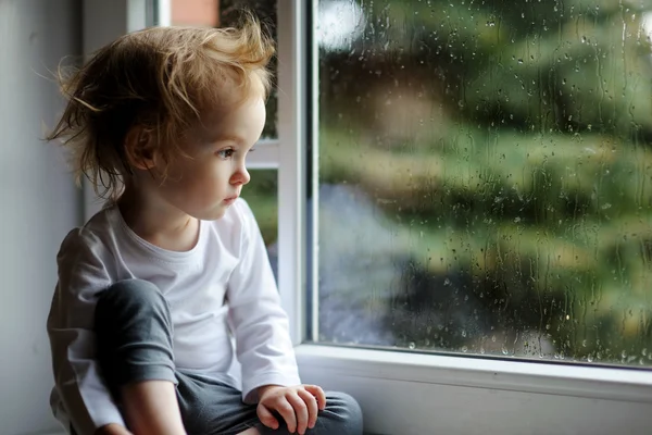 Toddler girl looking though  window — Stock Photo, Image