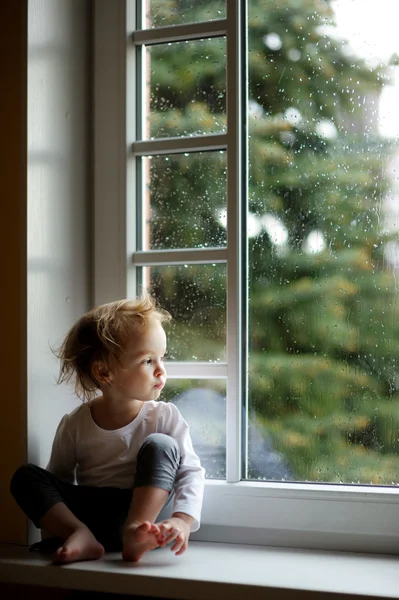 Tout-petit fille regardant par la fenêtre — Photo