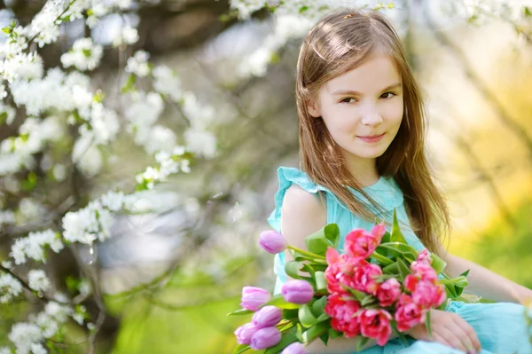 Söt liten flicka som håller tulpaner — Stockfoto