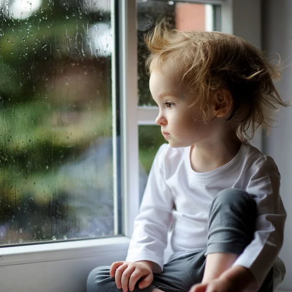 Toddler girl looking though  window — Stock Photo, Image