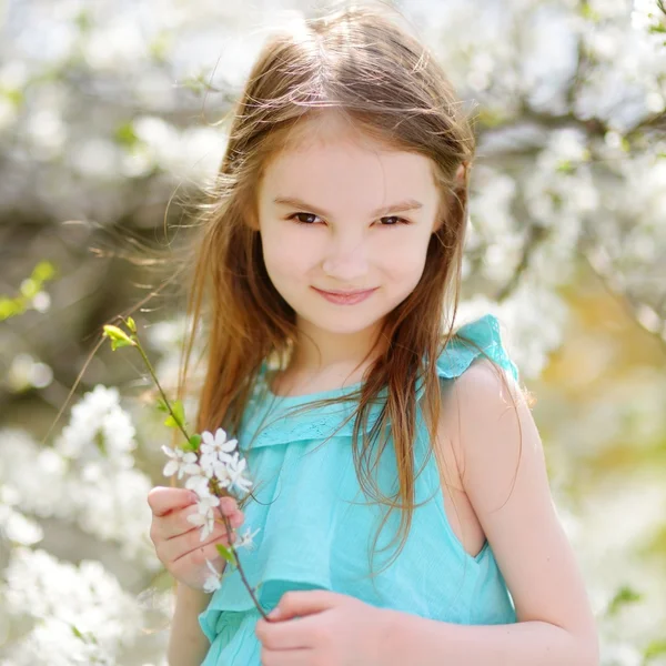 Kleines Mädchen im blühenden Kirschgarten — Stockfoto