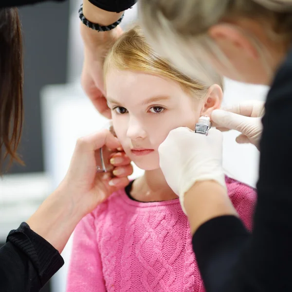 Little girl having ear piercing Stock Photo by ©MNStudio 97222044