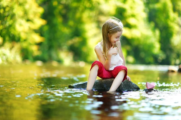 Девушка играет с бумажной лодкой — стоковое фото