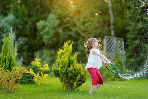 Menina brincando com uma mangueira de jardim — Fotografia de Stock