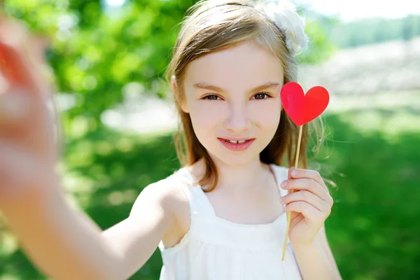 Chica con corazón de papel en un palo — Foto de Stock