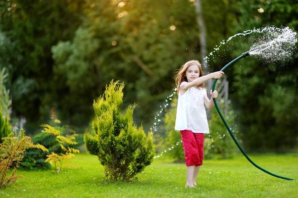 Menina brincando com uma mangueira de jardim — Fotografia de Stock