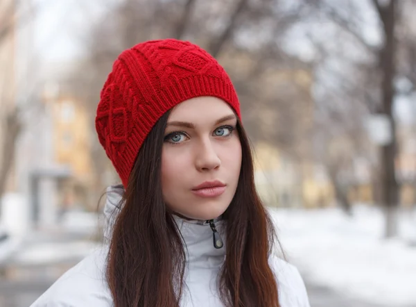 Retrato de una hermosa joven con una gorra roja en el paisaje urbano de primavera de fondo  . —  Fotos de Stock