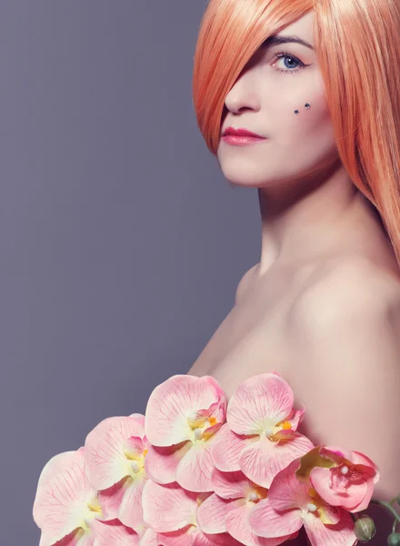 Retrato de bela jovem com flores de orquídea — Fotografia de Stock