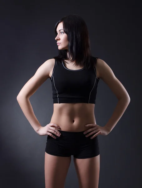 Fitness woman standing against black background — Stock Photo, Image