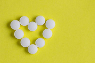 Sarı arka planda hapların kalbi.