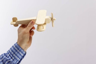 Beyaz arka planda bir iş adamının elindeki ahşap bir uçak modeli..