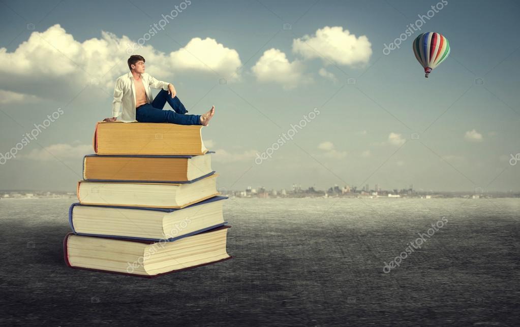 Young man sitting on books — Stock Photo © papa42 #64951413