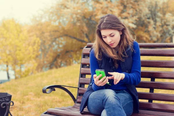 Vrouw met behulp van mobiele telefoon in park — Stockfoto