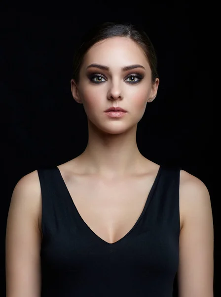 Beauty portrait of young woman  on black background. Brunette girl with evening female makeup and black dess.