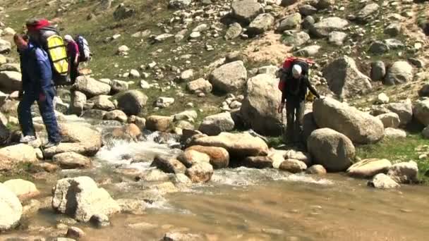 Turistas que atravessam o rio montanha — Vídeo de Stock