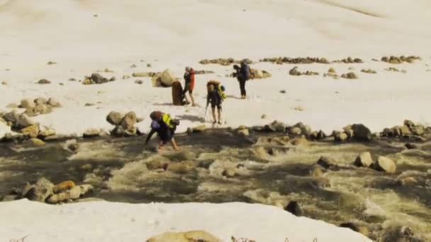 Caminhantes cruzando um rio de montanha — Vídeo de Stock