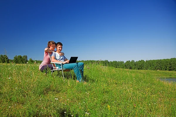 Casal na natureza assistindo em um laptop — Fotografia de Stock