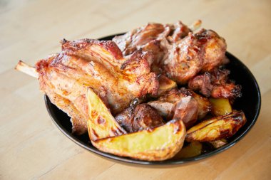 Tahta bir masada siyah tabakta patates kızartması.