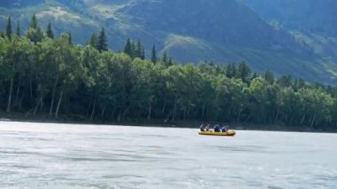 Engebeli nehirde arka planda güzel bir orman kıyısı olan bir sal teknesinin videosu. 