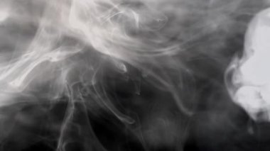 Karanlık arkaplanda yavaşça hareket eden dumanın görüntüleri