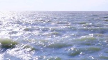 Deniz suyu dalgaları parlak güneş ışığında hareket ediyor.