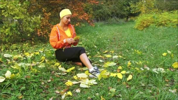 Chica sentada en otoño parque — Vídeo de stock