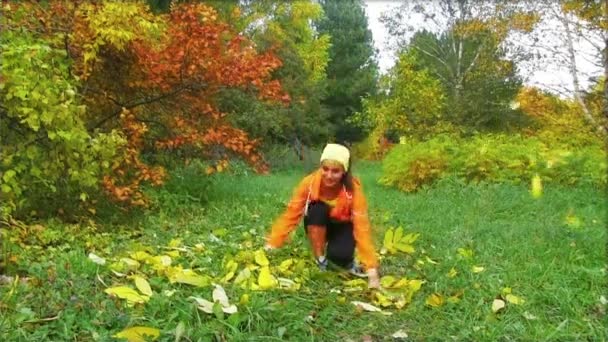 Mujer feliz lanzando hojas de otoño — Vídeos de Stock