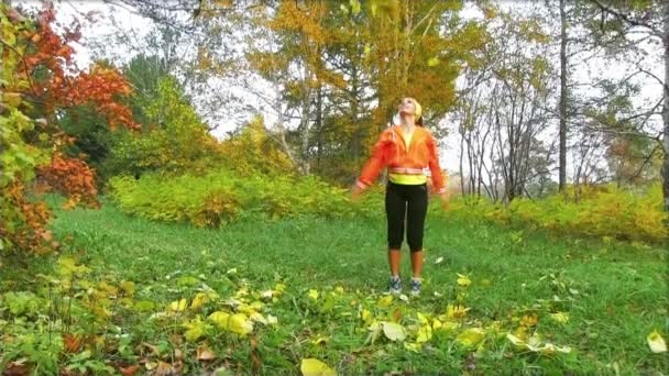 Mujer feliz lanzando hojas de otoño — Vídeo de stock