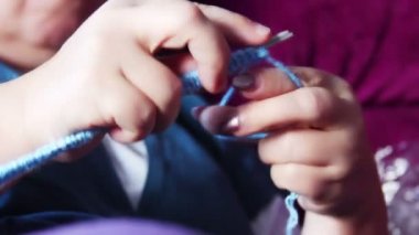 Kadın evde örgü örüyor.