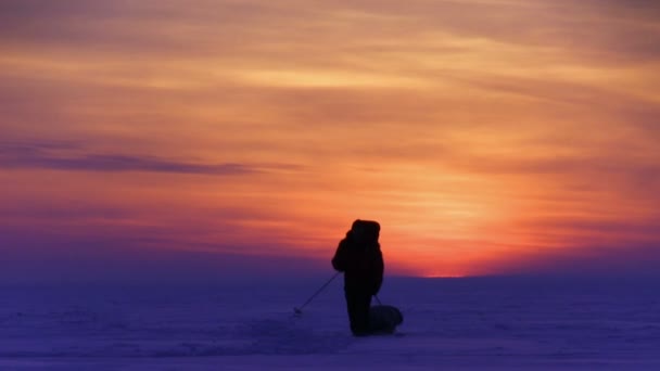 L'homme va au coucher du soleil sur le désert de neige 