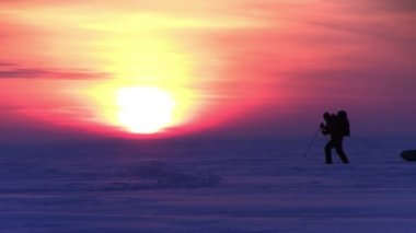Adam gün batımında kar çölde