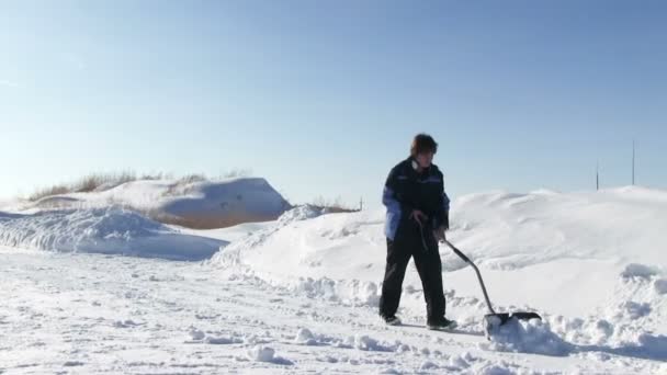 Άνθρωπος φτυαρίζει το χιόνι από το δρόμο — Αρχείο Βίντεο