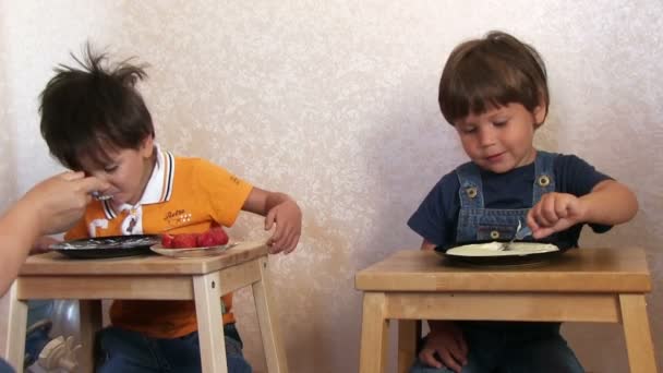 Два веселых мальчика едят кашу — стоковое видео