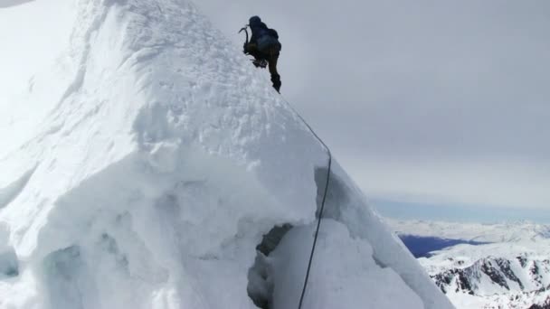 El montañista desciende de la cima de la montaña — Vídeo de stock