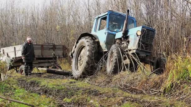 Рабочие с приклеенным трактором на дороге — стоковое видео