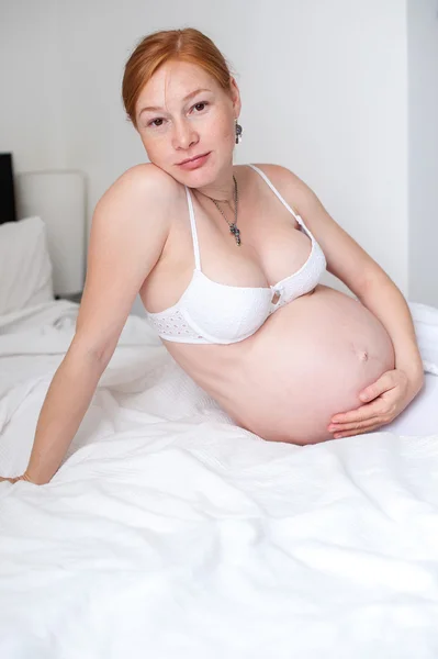 Mulher grávida de cabelos vermelhos na cama — Fotografia de Stock