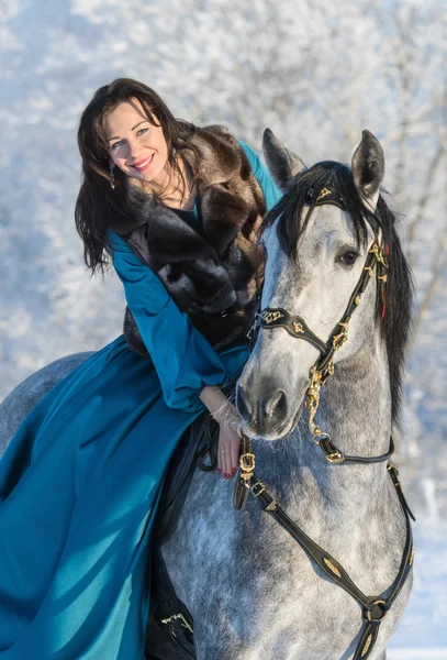 Žena v modrých šatech na šedý hřebec — Stock fotografie