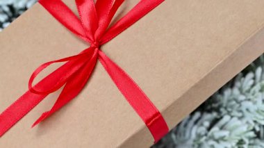 Kırmızı kurdeleli ve fiyonklu bir hediyenin yakın çekim videosu.