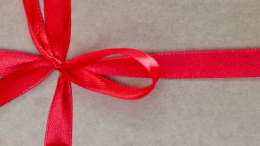 Kırmızı kurdeleli ve fiyonklu bir hediyenin yakın çekim videosu.