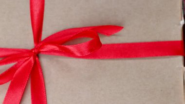 Kırmızı kurdeleli ve fiyonklu bir hediyenin yakın çekim videosu.