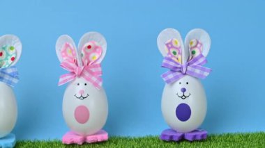 Yeşil çimlerin üzerinde yumurtaları olan tavşanların güzel bir Paskalya süslemesinin videosu..