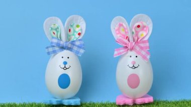 Yeşil çimlerin üzerinde yumurtaları olan tavşanların güzel bir Paskalya süslemesinin videosu..