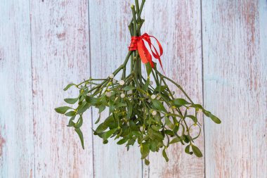 Kırmızı kurdeleli bir ökseotu buketinin yakın plan fotoğrafı.