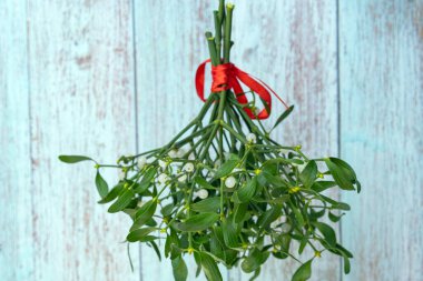 Kırmızı kurdeleli bir ökseotu buketinin yakın plan fotoğrafı.