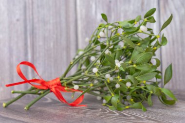 Kırmızı kurdeleli bir ökseotu buketinin yakın plan fotoğrafı.