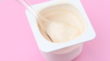 Pembe arka planda kaşıkla yoğurt videosu.