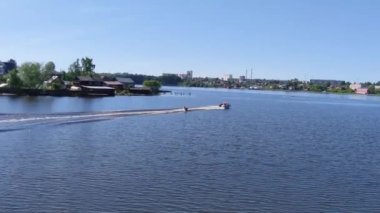 Nehirde motorlu teknenin arkasında borular var.